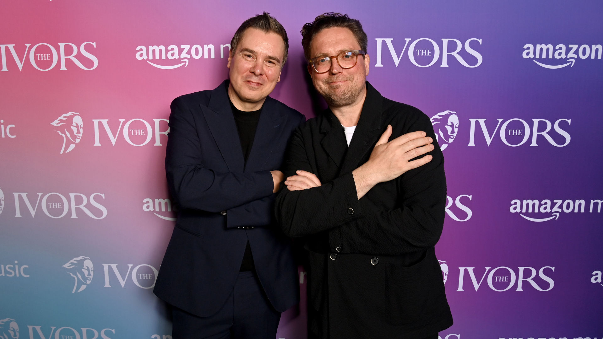 Roberto Neri and Tom Gray standing in font of a brand board with The Ivors and Amazon Music logos